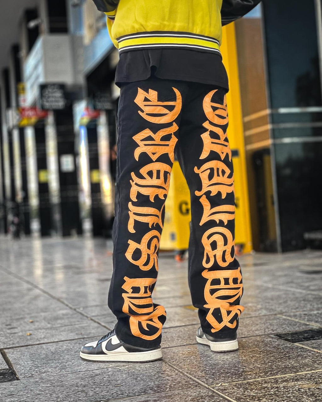 BLACK JEANS WITH ORANGE GOTHIC LETTERING FASHION STATEMENT APPAREL